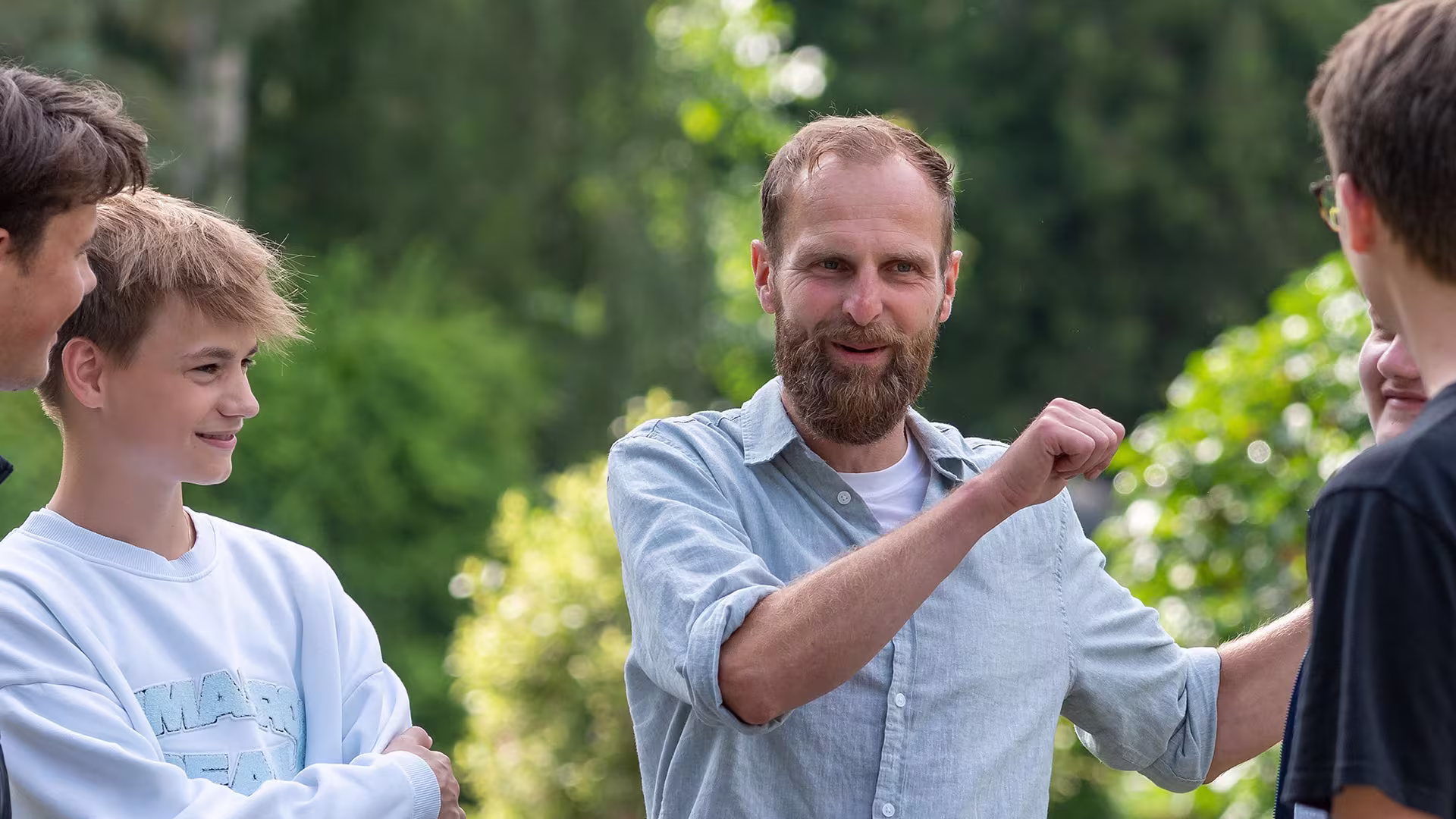 Lehrer erklärt Schülern einen Sachverhalt im Freien
